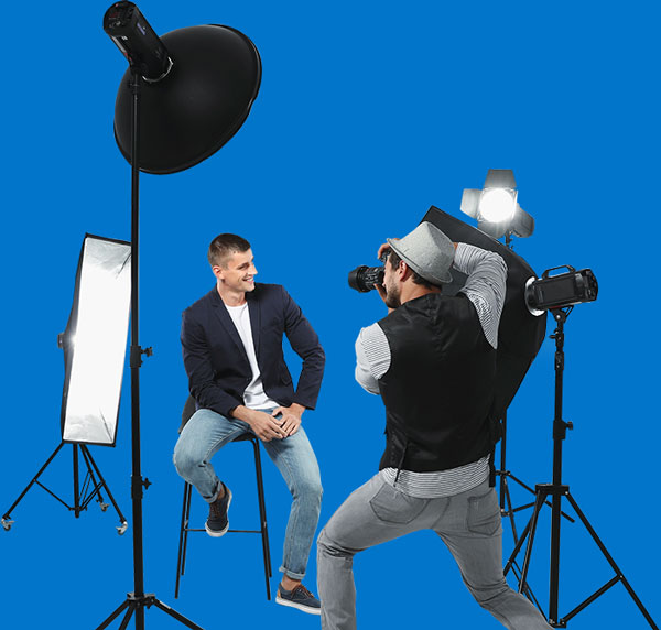 photographer taking a headshot of another man sitting on a stool